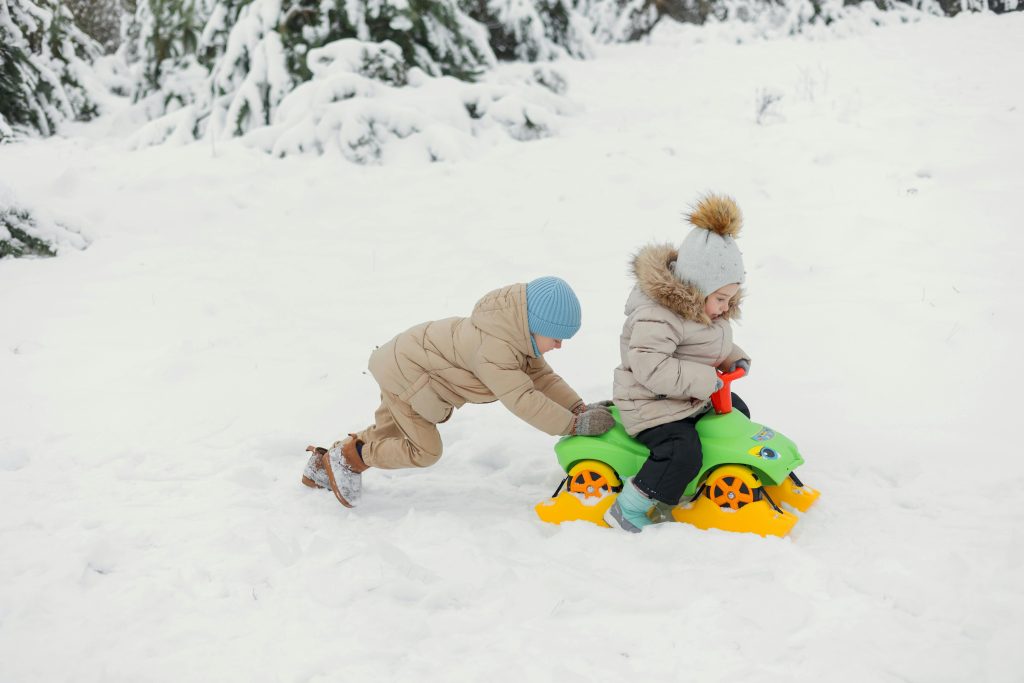 two children riding on a toy in the snow
