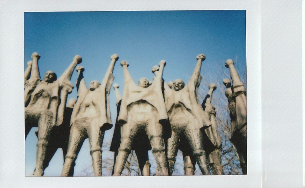 series of statues of people with arms raised